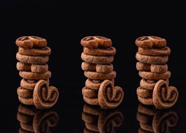 Kurabiyeler toz şekerli kalp şeklinde. Lezzetli, taze kurabiyeler siyah arka planda bir sütuna istiflenir. Tatlı nefis..