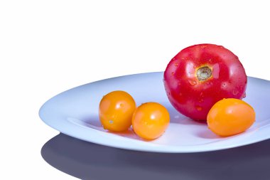 Bir kırmızı domates ve beyaz bir tabakta üç sarı domates..