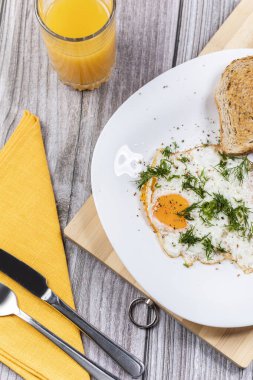 Maydanoz ve domatesle servis edilen bir tabakta kızarmış yumurta. Lezzetli portakal suyu kahvaltısı konsepti.