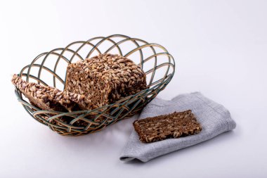 Beyaz arka planda hasır bir kasede ayçiçeği tohumlu lezzetli çavdar ekmeği. Lezzetliyediklerimizve besinlerimiziiçerir..