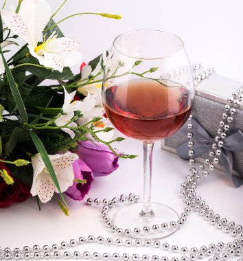 Mesaj için ayrılmış bir tebrik kartı için arka plan. Beyaz bir arkaplanda, bir bardak şarap, hediye kutuları ve çiçekler..