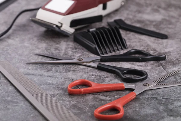 Barber tools are on the shelf in the salon. Accessories for cutting hair: scissors, combs and others are on the table.