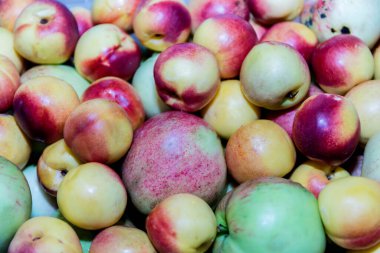 Sulu, olgun, pembe nektarinler (Prunuspersica) ve elmalar birbirinin üstünde uzanır.