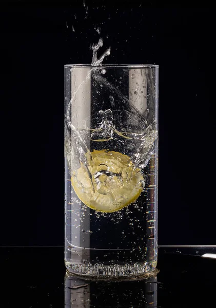 Uma Fatia Limão Cai Copo Água Fundo Preto — Fotografia de Stock