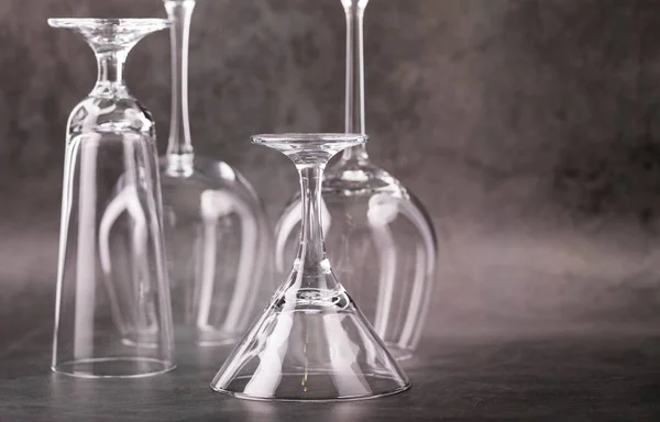 Glass wine glasses of various shapes and sizes on a gray background.