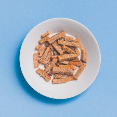 Gevrek rusk beyaz tabakta yemek saati bira. Mavi arka plan üzerinde üstten görünüm