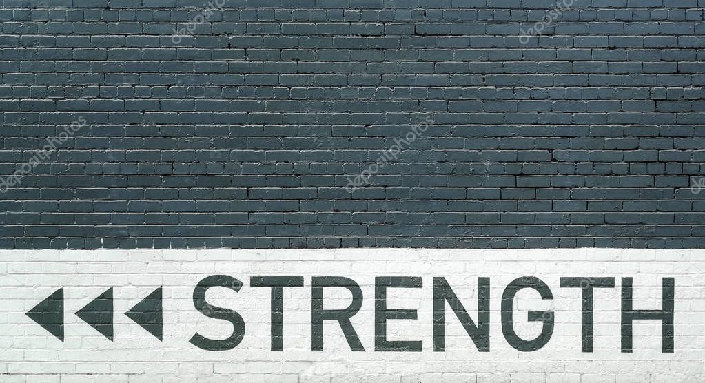 Strength motto over a gray brick wall