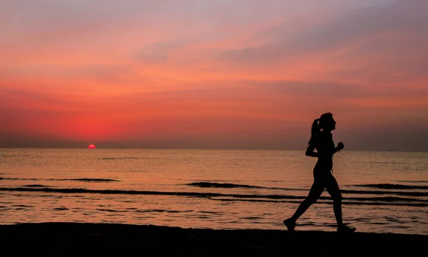 Sporty woman with pony tail running on the beach during sunrise