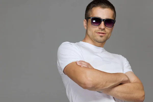 Man in sun glasses, in white cotton t-shirt closeup on gray backdrop. Modern garment front view. Textile design. — Stock Photo, Image