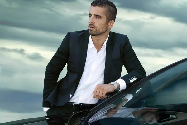 Porträt eines gutaussehenden Geschäftsmannes, der neben dem Auto vor der Tür steht Stockfoto
