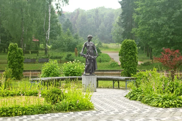 summer garden with a statue of a girl with a wreath in her hands
