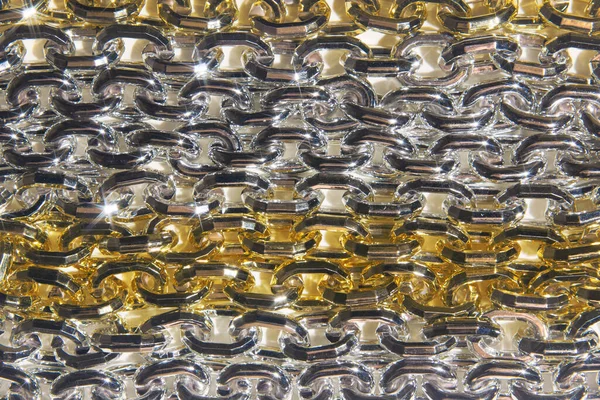 A gold silver chain and large cells lie on a white background.