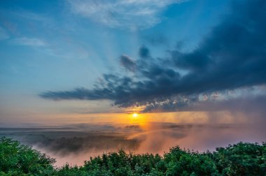 Köyün üzerinde sisli bir yaz sabahında gün doğumu