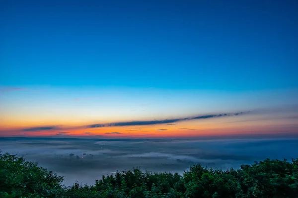 Morgendämmerung an einem nebligen Morgen auf einem Berg über dem Fluss — Stockfoto