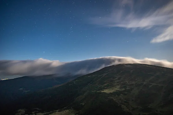 Panorama of the starry sky over the foggy mountains