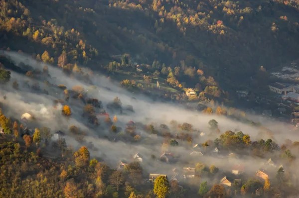 Casas e árvores no nevoeiro da manhã no outono — Fotografia de Stock