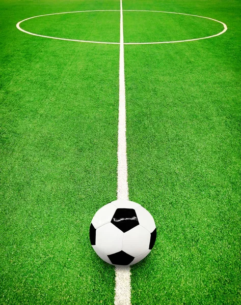 Perspective view of green football pitch with white lines and circle and soccer ball