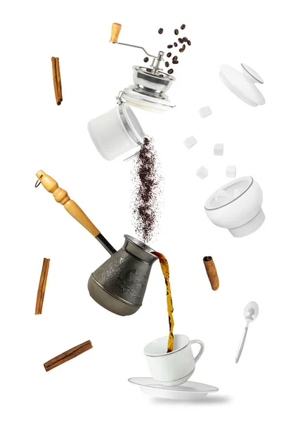 Coffee falling into cup. Flying coffee grounder and turkish brewing pot. Hot drink isolated on white background