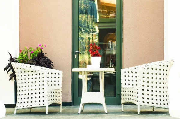Two chairs and small table with flowers. Outdoor cafe with cozy white armchairs