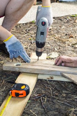 Elinde bir marangoz işçi vidalar bir cıvata bir ahşap panosunda inşaat sitesinde bir tornavida ile yakın çekim.