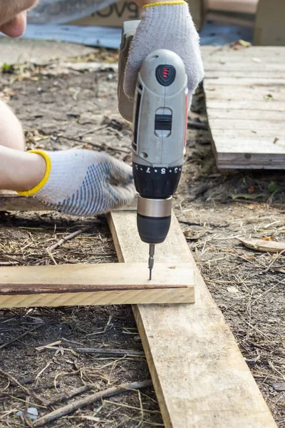 木匠工人的手紧螺丝在一个木板螺栓在建筑工地用螺丝刀 — 图库照片