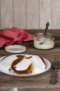 Süzme peynir ile Pancakes, ekşi krema beyaz bir tabak içinde.