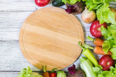 Daire kesme tahtası ve sebze Beyaz ahşap zemin üzerinde. Sağlıklı beslenme.