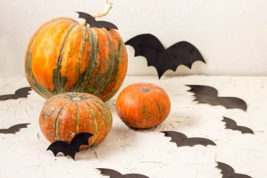 Turuncu kabak ve kağıt yarasalar üzerinde beyaz masa, Cadılar Bayramı kavramı.
