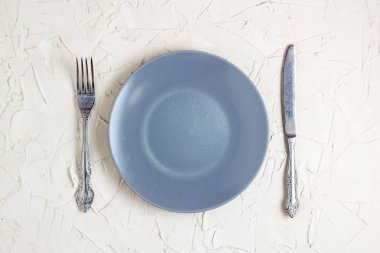 Gri tabak, çatal ve bıçak beyaz zemin üzerine boşaltın. Metin alanı olan üstten görünüm.