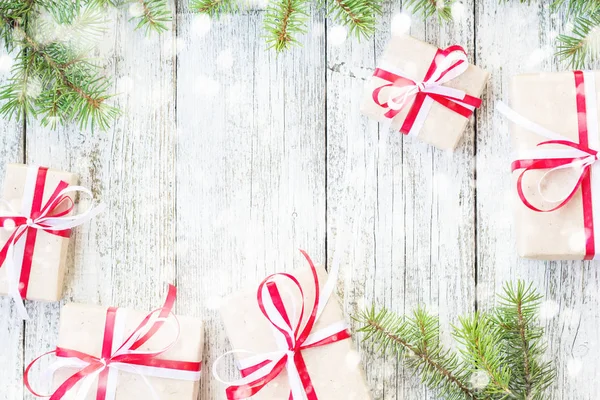 Sınır Noel hediye kutuları ve köknar ağacı dalı kar ahşap masa üzerinde. Kopya alanı ile üstten görünüm
