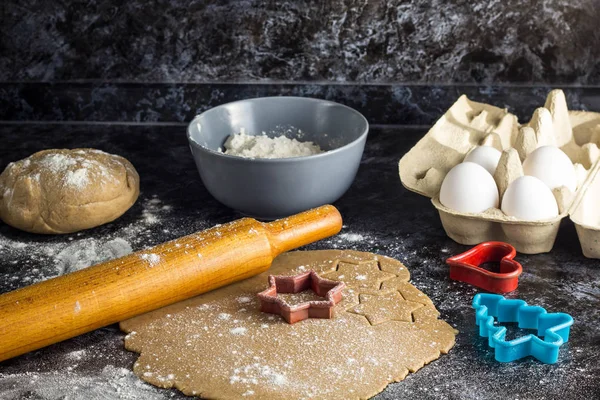 Cooking Christmas gingerbread cookies with ingredients on a dark background.