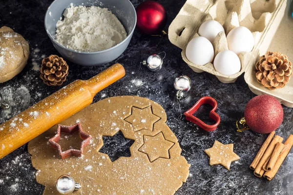 Cooking Christmas gingerbread cookies with ingredients on a dark background.