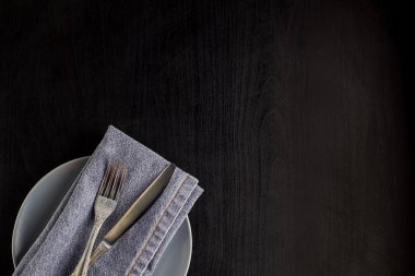 siyah arka plan üzerinde boş plaka peçete çatal ve bıçak ile masa ayarı