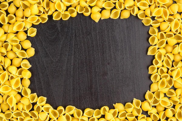 Rahmen eines Haufens von Conchiglie-Muscheln auf schwarzem Hintergrund mit Copyspace — Stockfoto