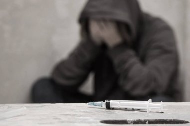 Arka planda oturan odak adam uyuşturucu bağımlısı dışarı ile şırınga