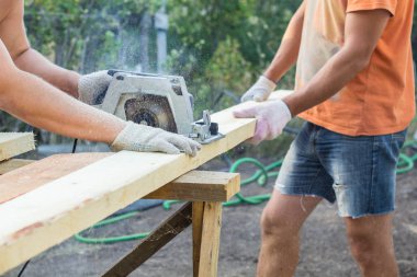 İnşaatçılar tahtayı dairesel testereyle kesiyorlar.