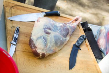 Taze ve çiğ et. Kesme Tahtası üzerinde bıçaklı kuzu bacağı