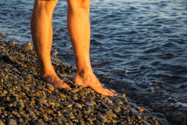 gün batımında çakıl sahilde yalnız yürüyen adam