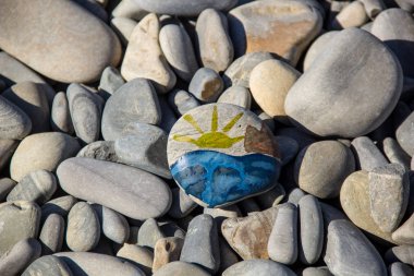 Parlak güneş çakıl üzerine boyanmış. Çakıl taşları ve deniz arka planı.