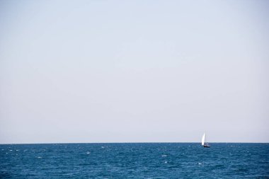 Ufukta açık denizde büyük beyaz yelkenli küçük yelkenli yat