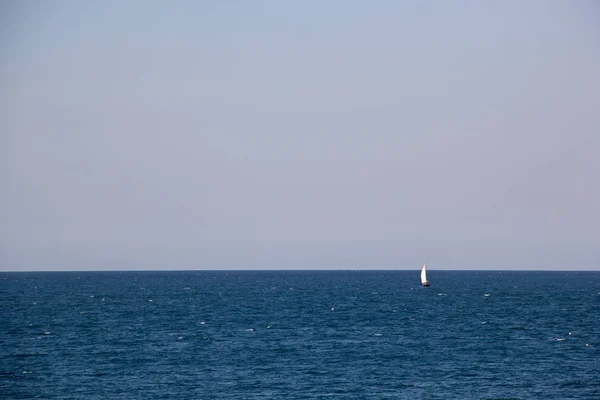 Pequeño yate de vela con grandes velas blancas en mar abierto en el horizonte — Foto de Stock