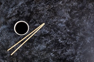 Siyah arka plan üzerinde Japon suşi çubukları ve soya sosu. Copyspace ile üst te görüş