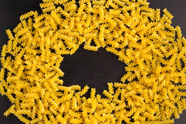 Rahmen eines Haufens Nudelspirale fusilli auf schwarzem Hintergrund mit Copyspace — Stockfoto