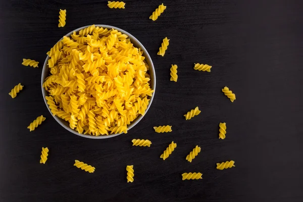 Vista superior de fondo negro con cuernos de pasta cruda italiana en tazón con espacio para copiar — Foto de Stock