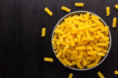 Kopya alanı ile kase İtalyan çiğ makarna spiral fusilli ile siyah arka plan üst görünümü