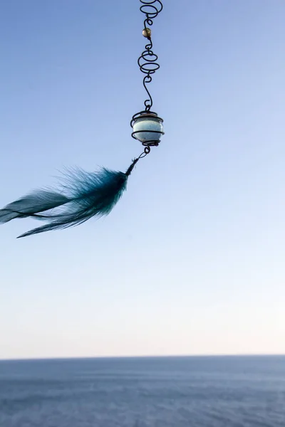 海の背景にガラスのボールと羽を持つ装飾的なペンダント — ストック写真