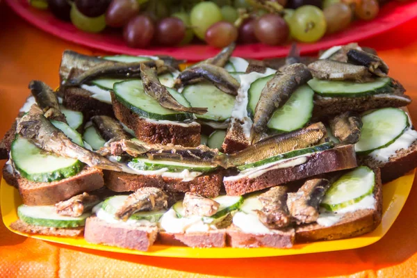 Sandwiches with smoked sprats and fresh cucumbers on an orange background — Stock Image Sandwiches with smoked sprats and fresh cucumbers on an orange background Stock Photo