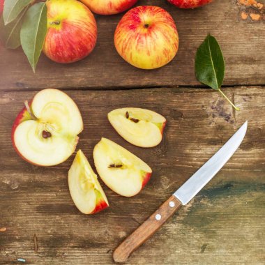 Kırmızı elma dilimli ve eski ahşap masa üzerinde bıçak