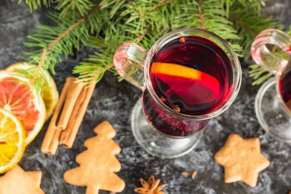 Vino caliente de Navidad con galletas de jengibre naranja canela clavo de olor anís y abeto en la mesa oscura — Foto de Stock