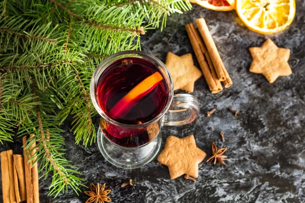 Vino caliente de Navidad con galletas de jengibre naranja canela clavo de olor anís y abeto en la mesa oscura — Foto de Stock